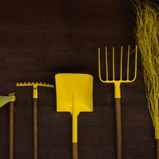Some bright yellow garden tools leaning against a wall