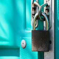 A bringht green door with a locked padlock on it