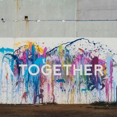 A wall with brightly coloured paints splashed on it with the word together in front