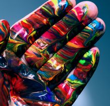 The open palm and fingers of a left hand covered in brightly coloured abstract patterns